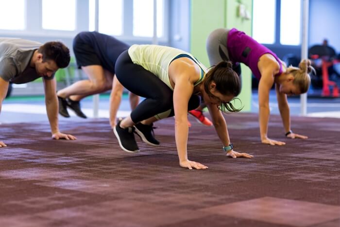 group of people doing burpees shown in jumping squat position