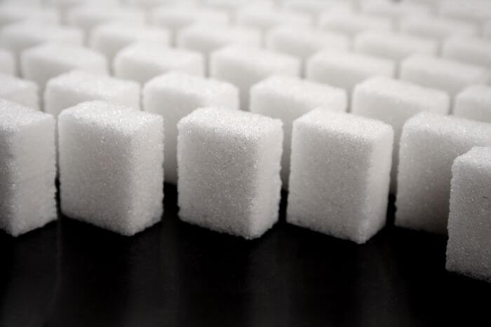 Close up of lots of sugar cubes on a dark background.