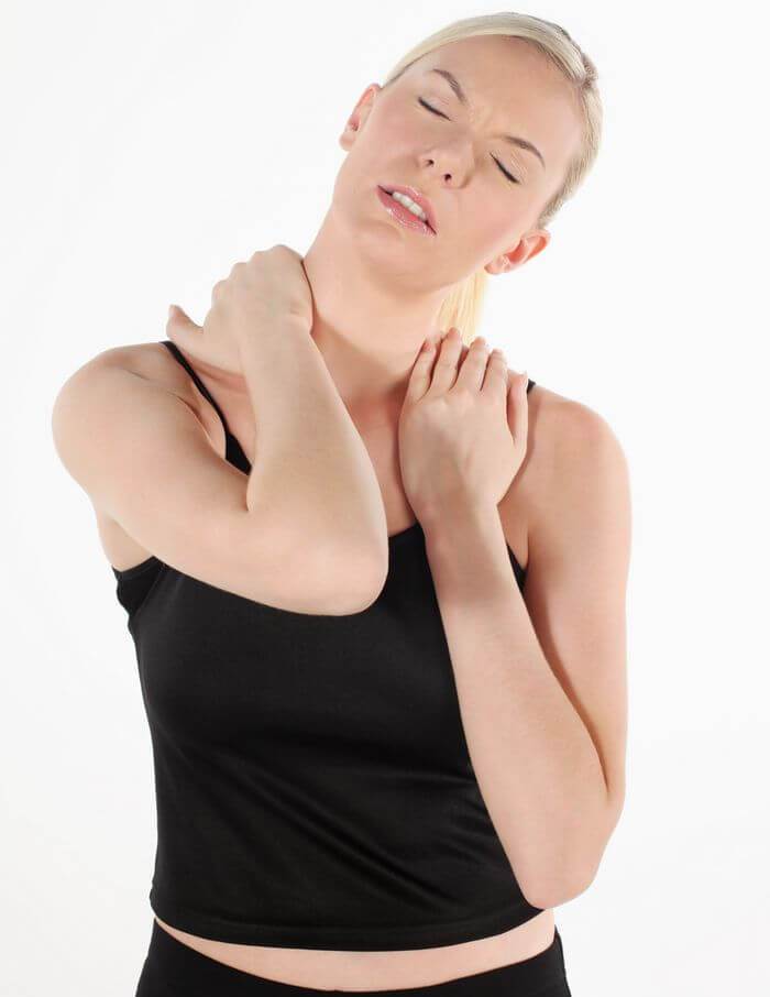 Woman holding her shoulders, seemingly in discomfort and pain.