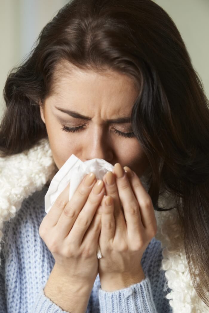 Woman sneezing into a tissue: Suffering from cold and infection.