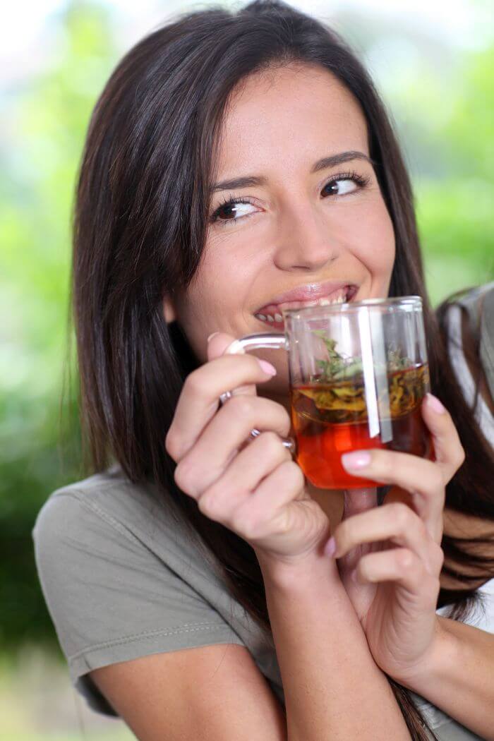Smiling woman drinking a herbal tea.